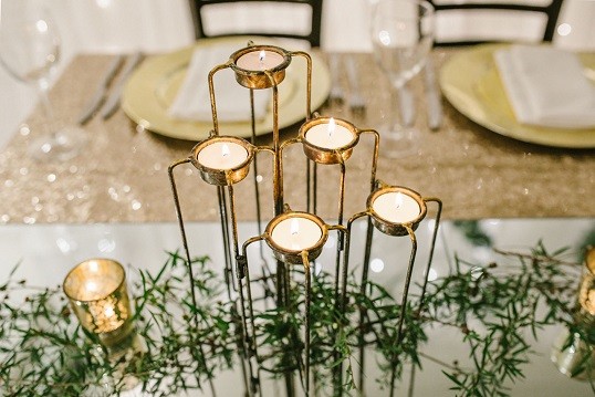 Brass candle holders and greenery on a styled reception table