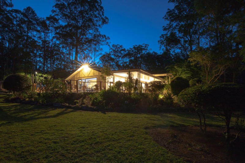 The venue building lit up at dusk with gardens in the foreground